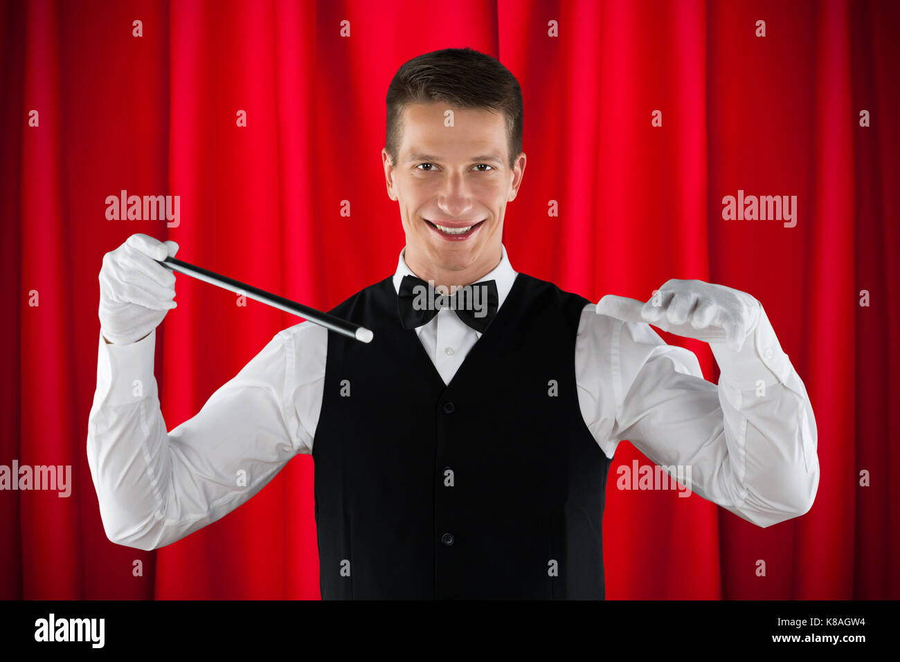 Young Male Magician Performing Magic With Magic Stick Stock Photo