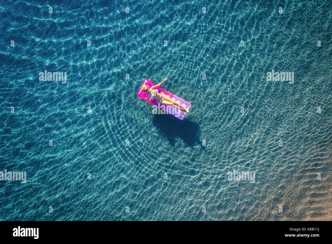 Aerial view of young woman swimming on the pink inflatable mattress in the transparent turquoise sea in Ichmeler,Turkey. Summer seascape with girl, az Stock Photo