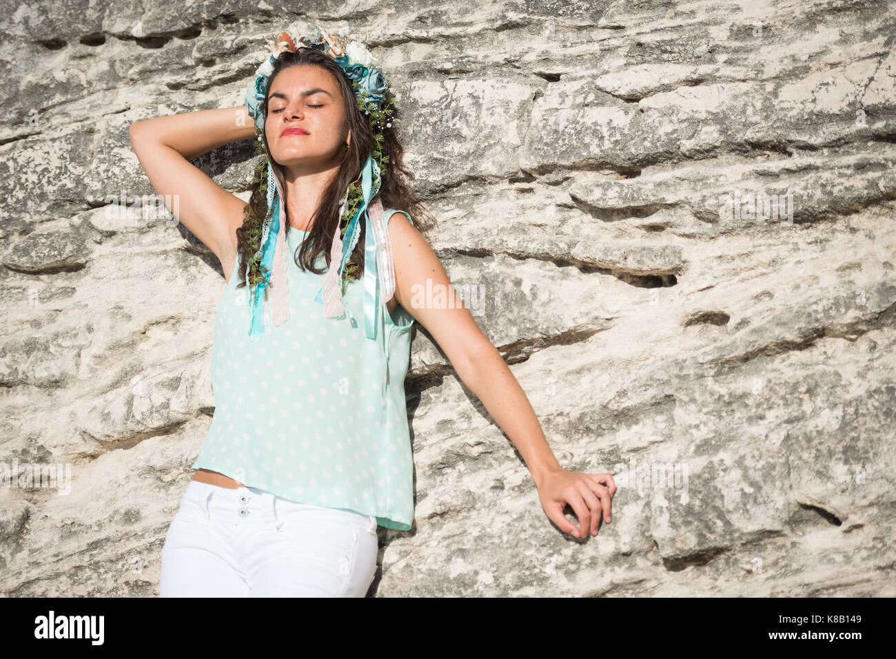 Young woman in blue shirt and white shorts with flower head band enjoying the moment Stock Photo