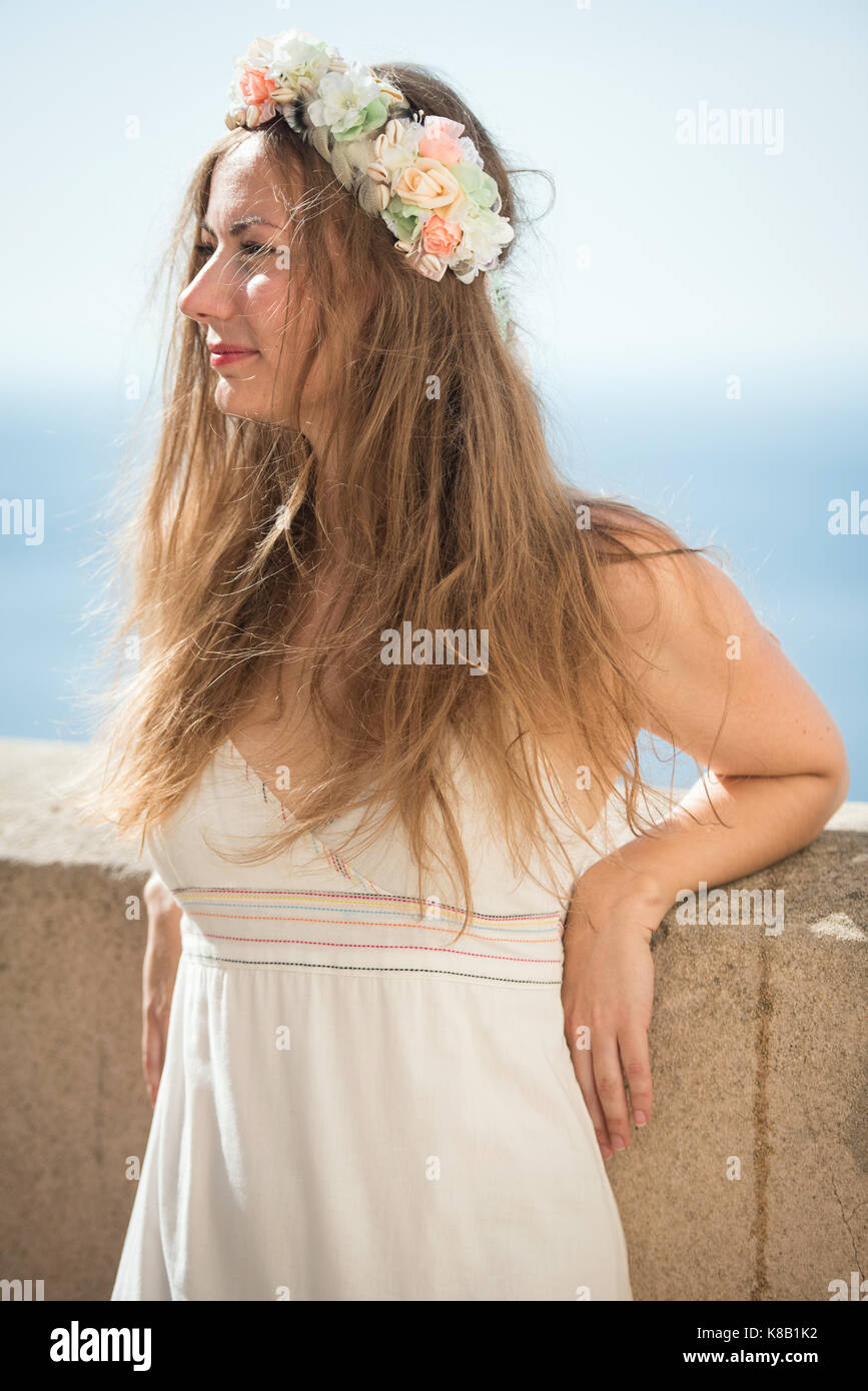 Detail of young woman in white dress with flower head band Stock Photo