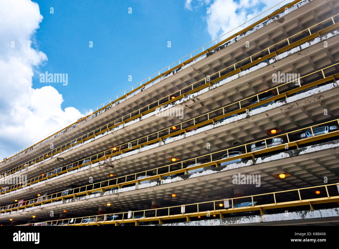 An exterior view of a multi-level parking garage against a blue sky with clouds. Stock Photo