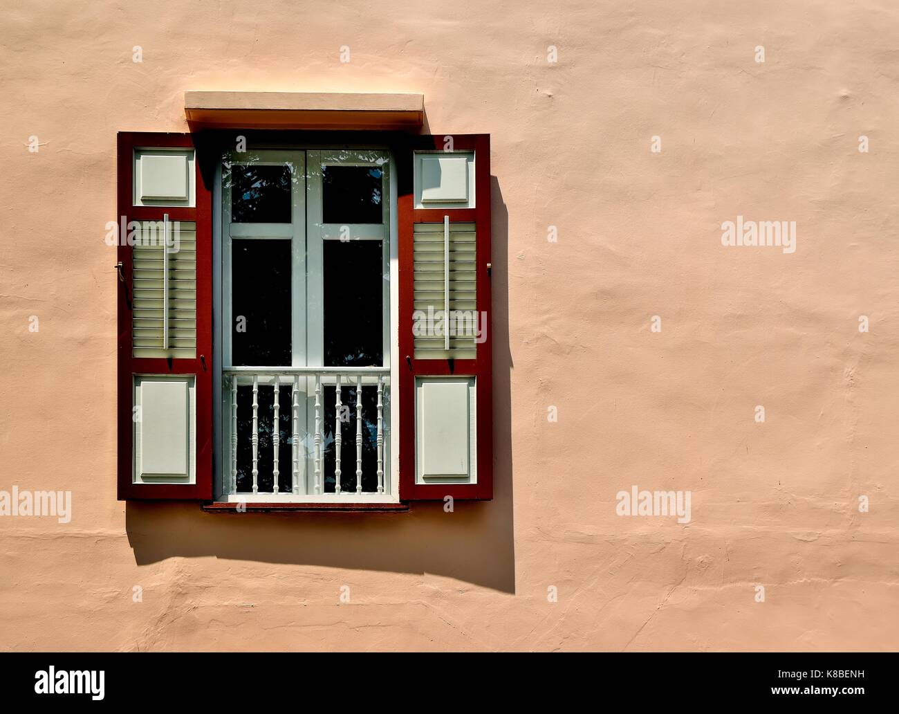 Singapore heritage window with red and white wooden louvered shutters perched on the side of a shop house in historic Armenian Street. Stock Photo