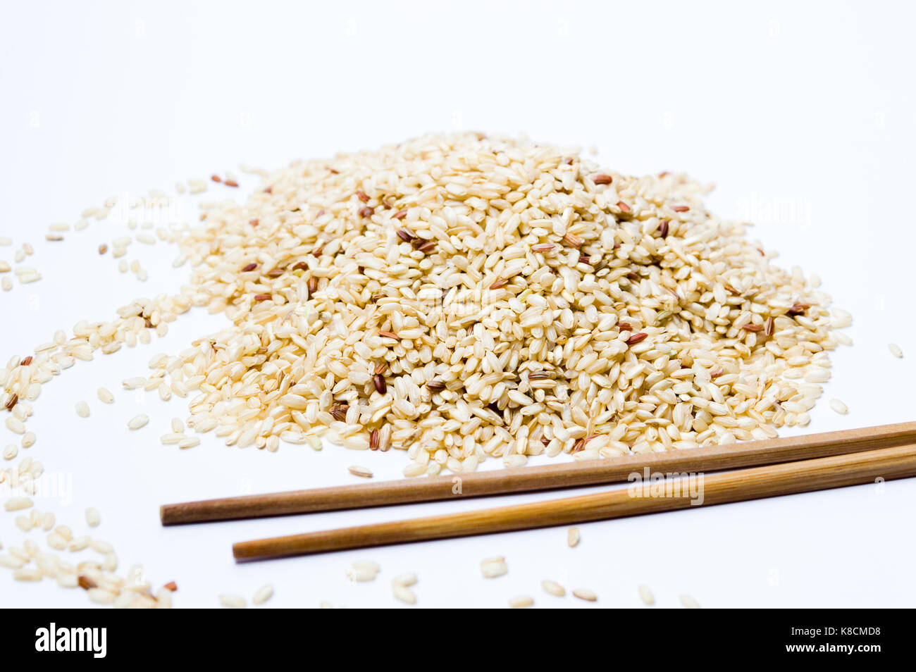 Yellow rice on a pile and wooden chopsticks on white Stock Photo