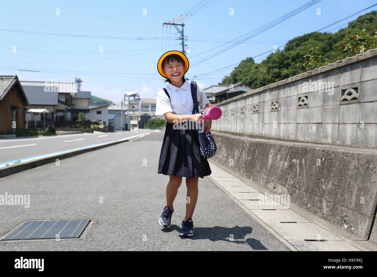 Elementary School Girl Walking on Road Stock Photo