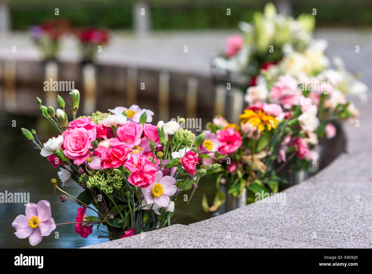 Flower bouquets for the dead beside a water pond at a memorial site Stock Photo Alamy