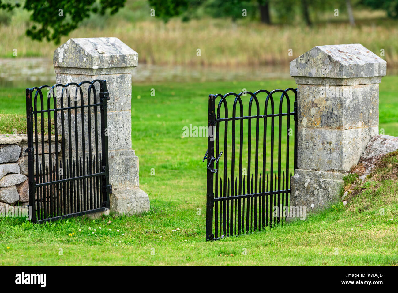 Open black iron gate sided by two stone pillars. Stock Photo