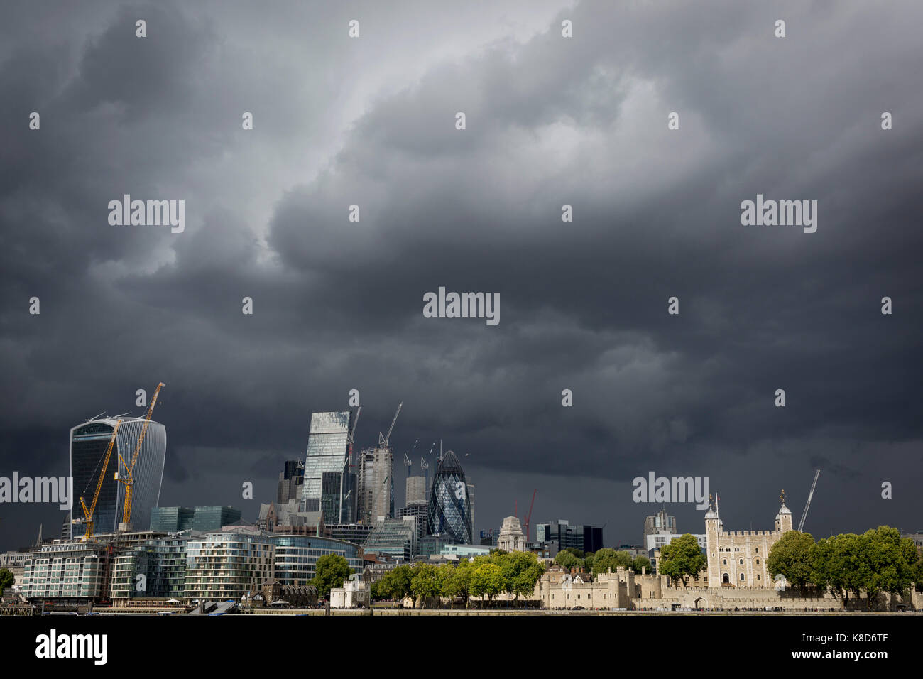 Storm clouds gather and dark times are ahead for the modern City of London (with the Norman-era Tower of London, right), on 14th September 2017, in London, England. The City is the historical financial district founded by the Romans in the 1st Century but faces a post-Brexit financial uncertainty. Stock Photo
