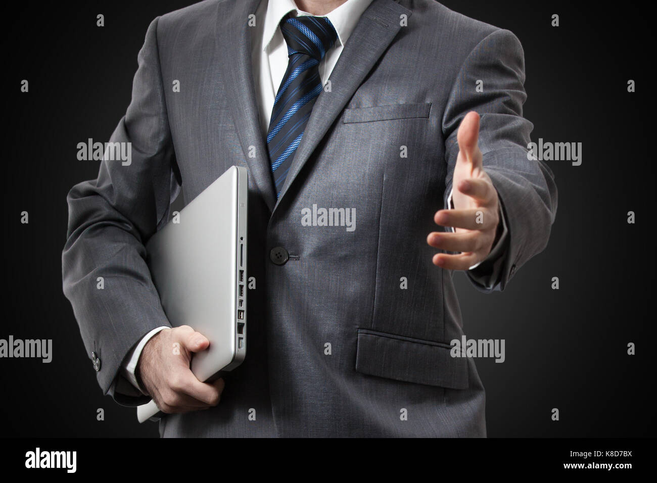 Businessman holding laptop and giving hand Stock Photo