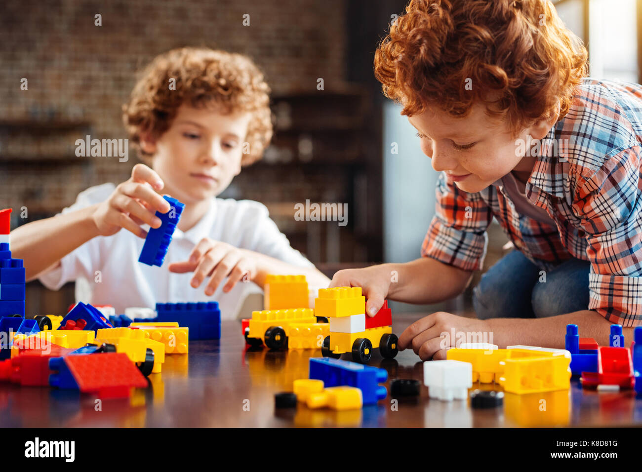 Cute ginger haired boy building car on table Stock Photo