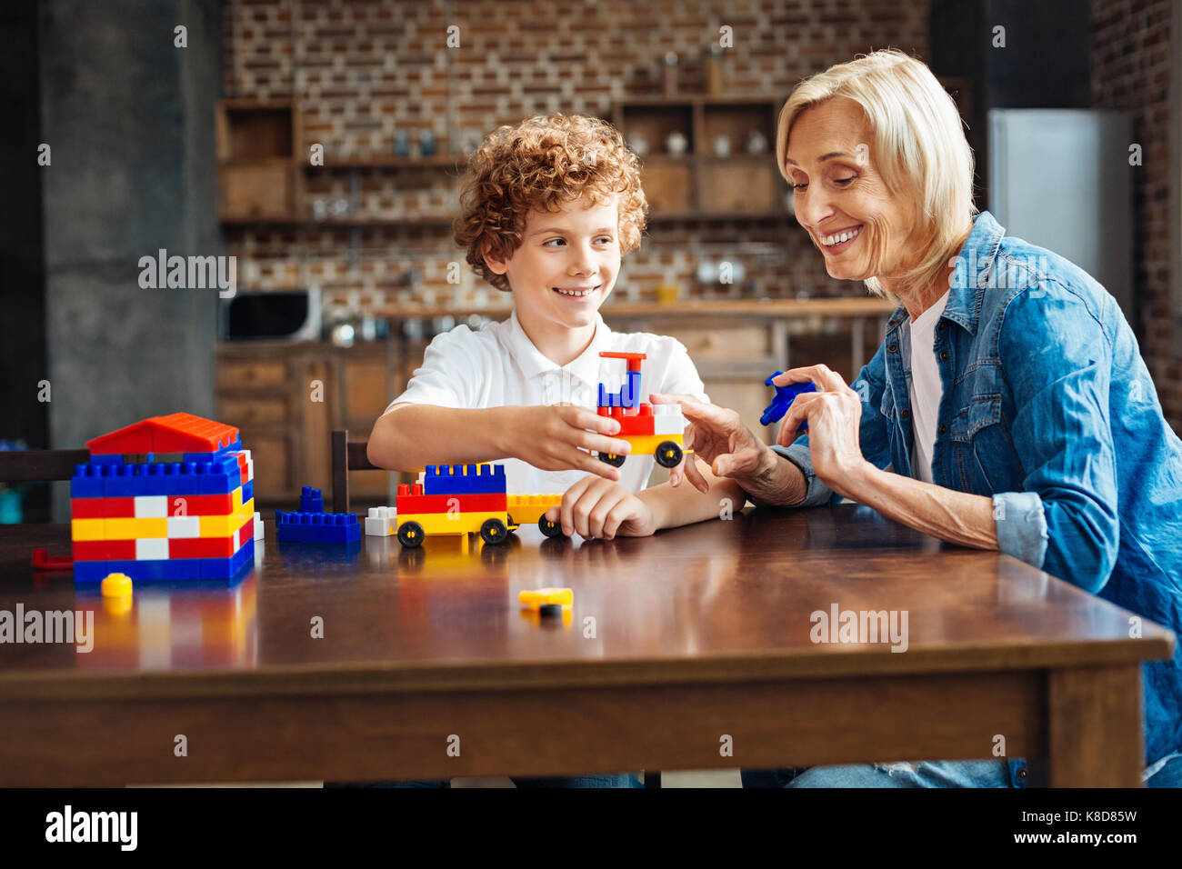 Radiant granny helping her grandson with car building Stock Photo