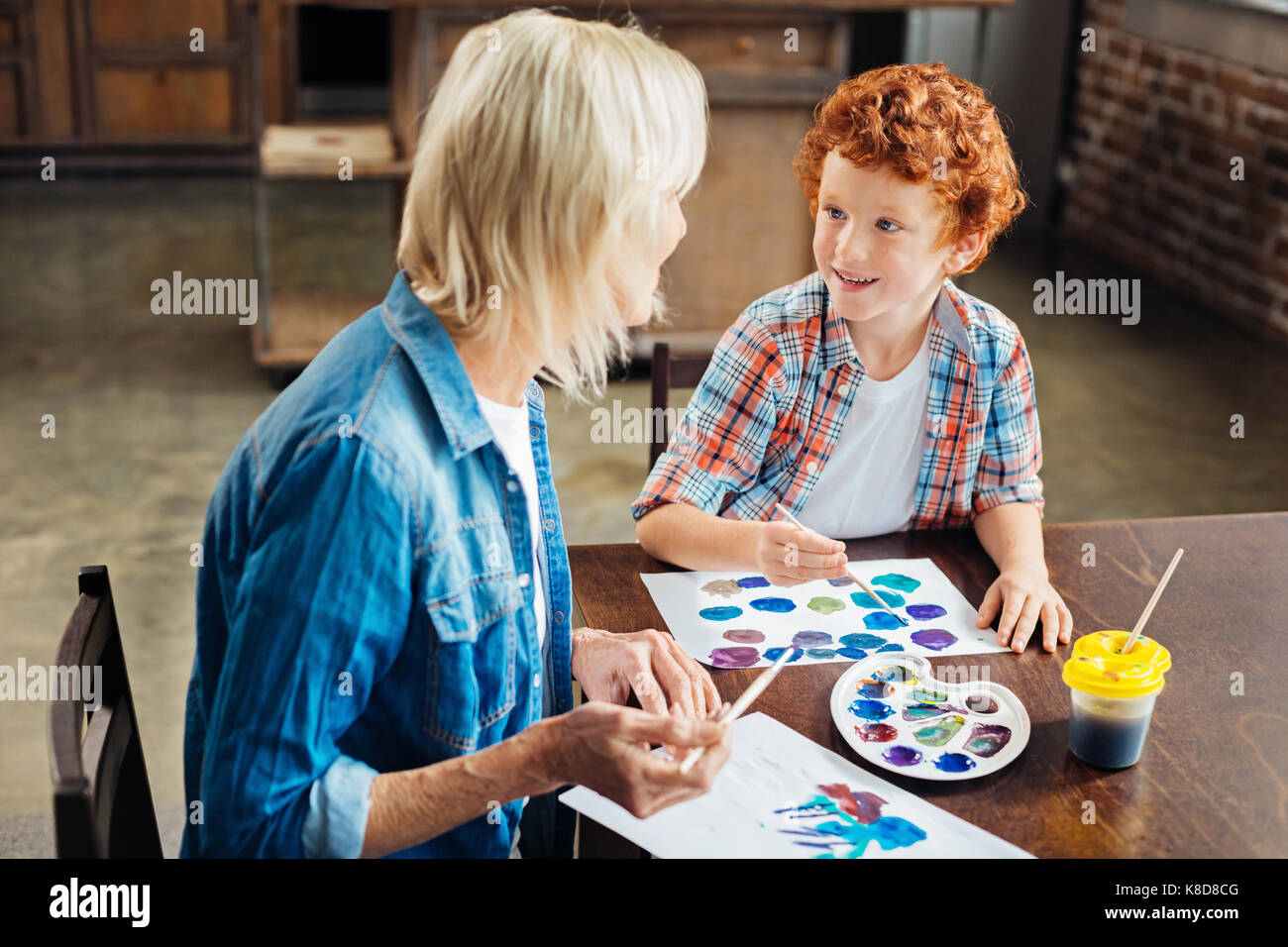 Adorable blue eyed kid gossiping with grandma Stock Photo