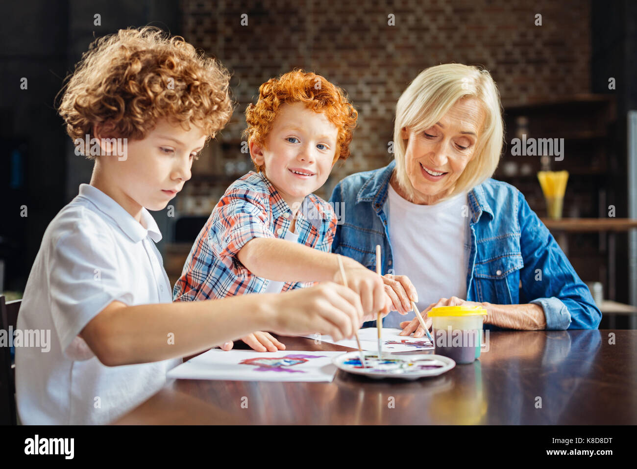 Cute ginger haired boy enjoying painting with brother and granny Stock Photo