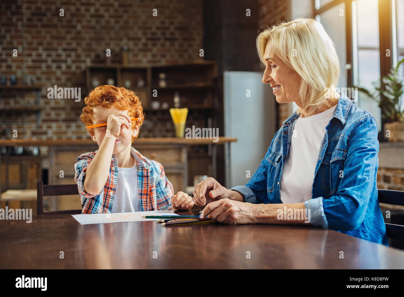Smiling grandma looking at grandson fooling with pencil Stock Photo