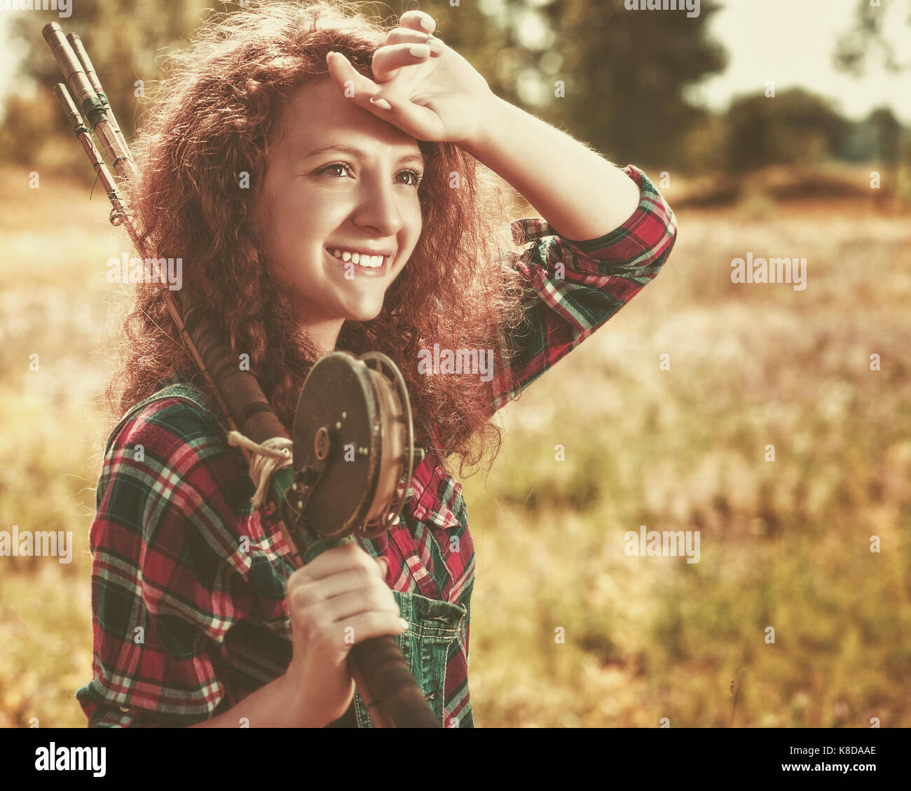 Fisher woman. Retro styled female portrait with wintage fishing pole, walking to the summer river Stock Photo