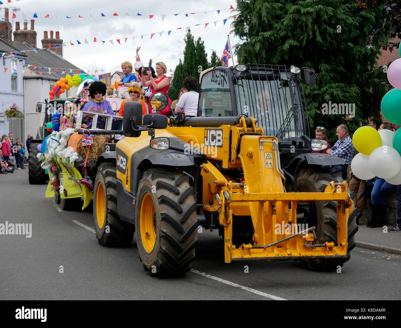 Yellow JCB tractor Barlow street carnival parade in Derbyshire England