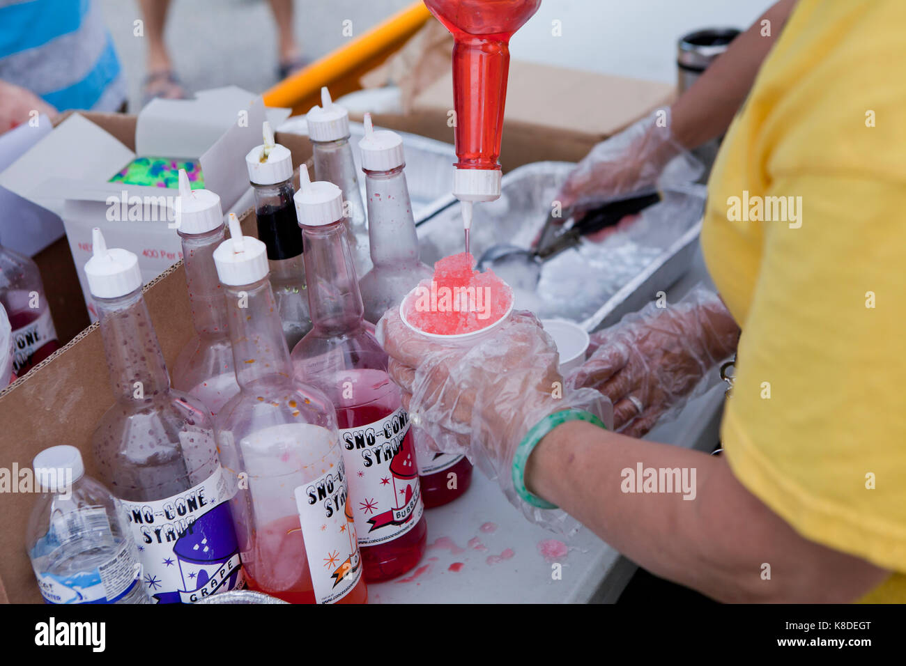Snow cone (shaved ice) vendor dripping flavored sugar syrup - USA Stock Photo
