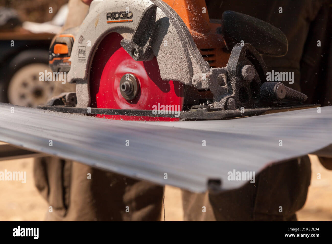 A construction worker using a handheld circular saw to cut through vinyl siding in Ontario, Canada. Stock Photo