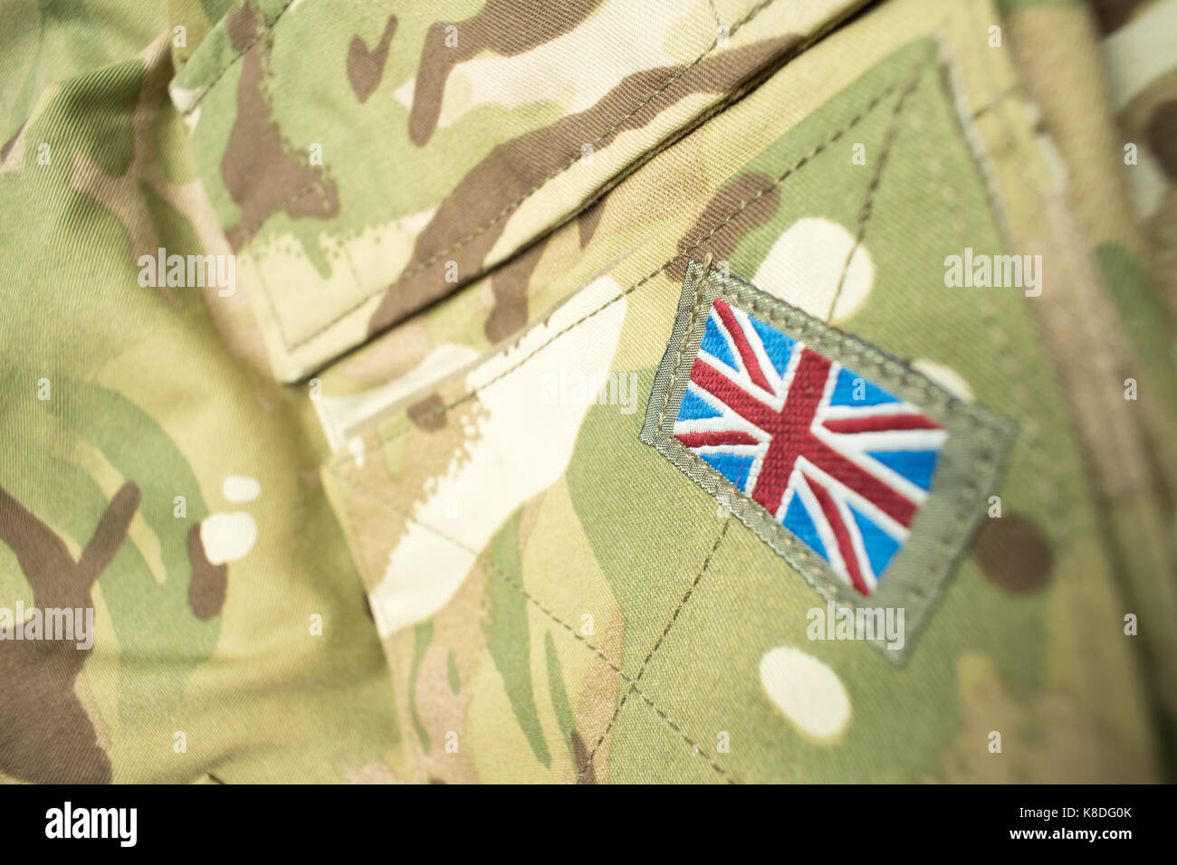 Union Jack / union flag badge on a camouflage British army uniform. Text / writing space surrounding badge. Stock Photo
