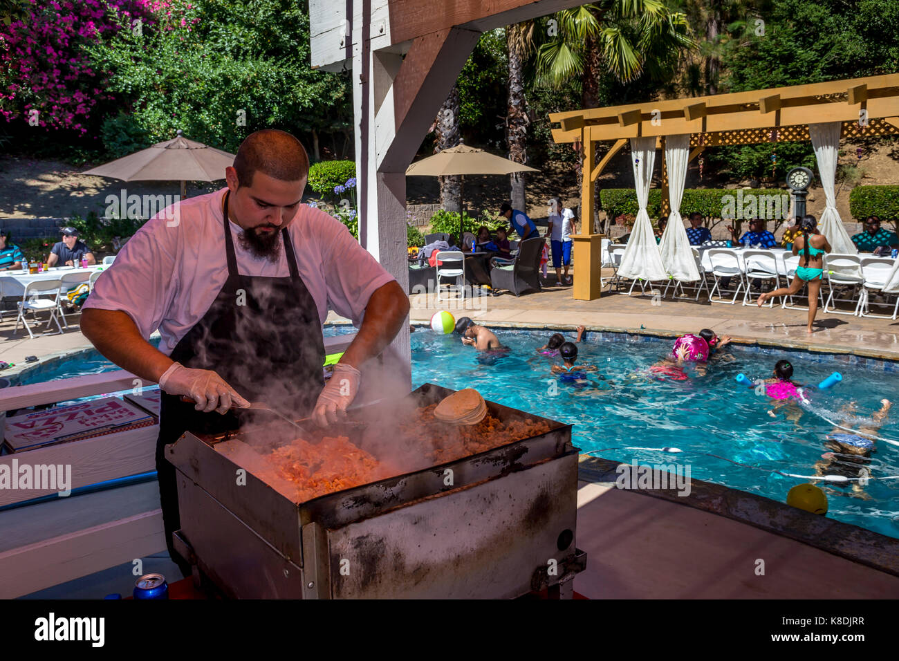 Hispanic man, cook, cooking on flat top grill, grilling meat, grilling meats, griddle, pool party, Castro Valley, Alameda County, California Stock Photo