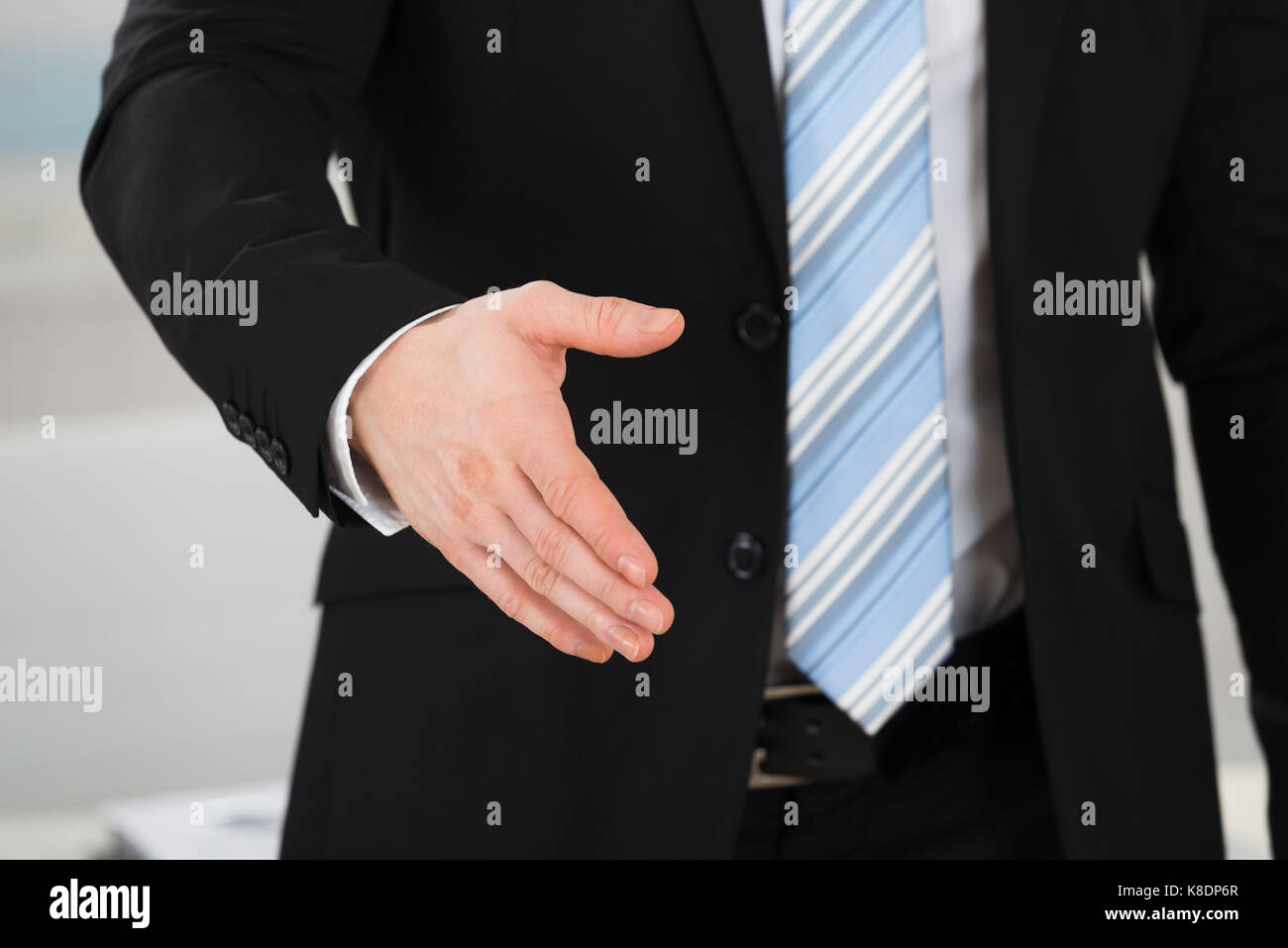 Midsection of businessman offering handshake while standing in office Stock Photo