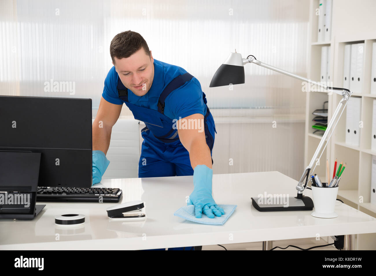 Mid adult male worker cleaning desk with sponge at office Stock Photo