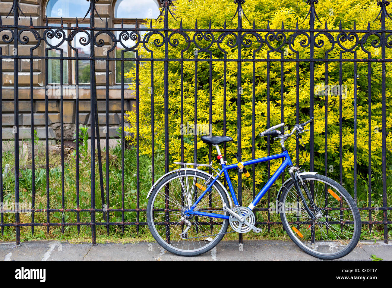 blue bicycle stand on lock at grunge metal fence. european street