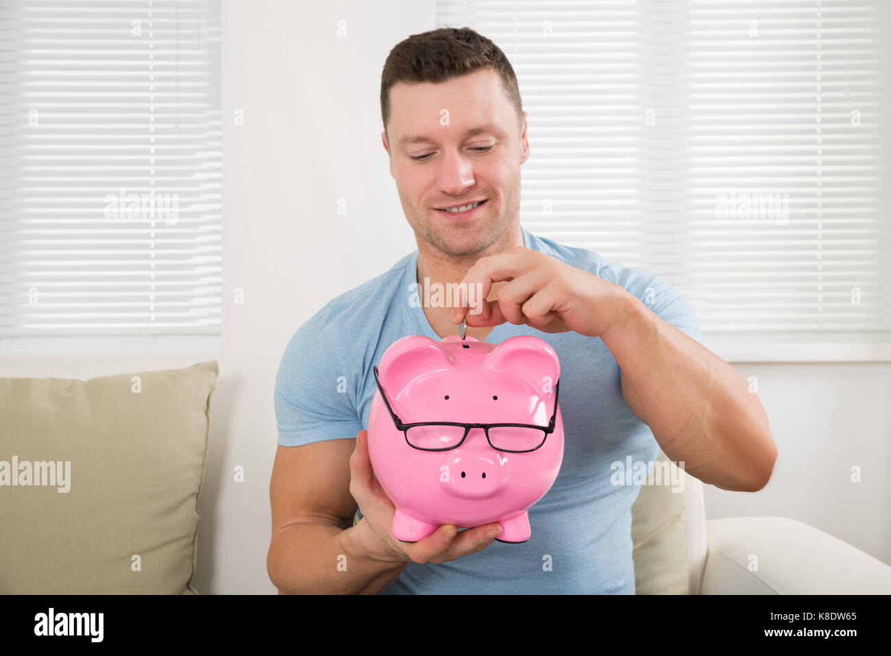 Happy mid adult man putting coin into piggy bank representing savings