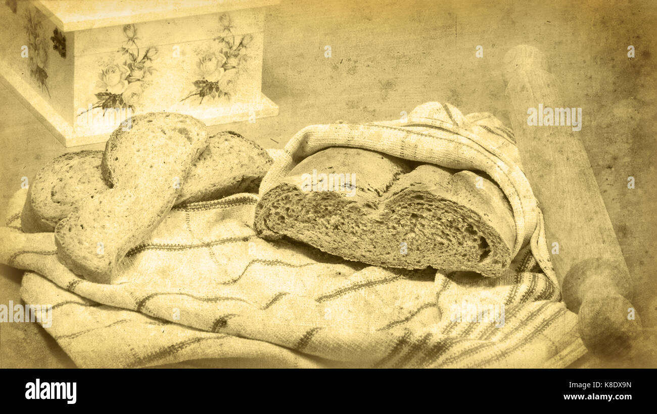 Bread loaf wrapped in a kitchen towel, two bread slices next to it, and