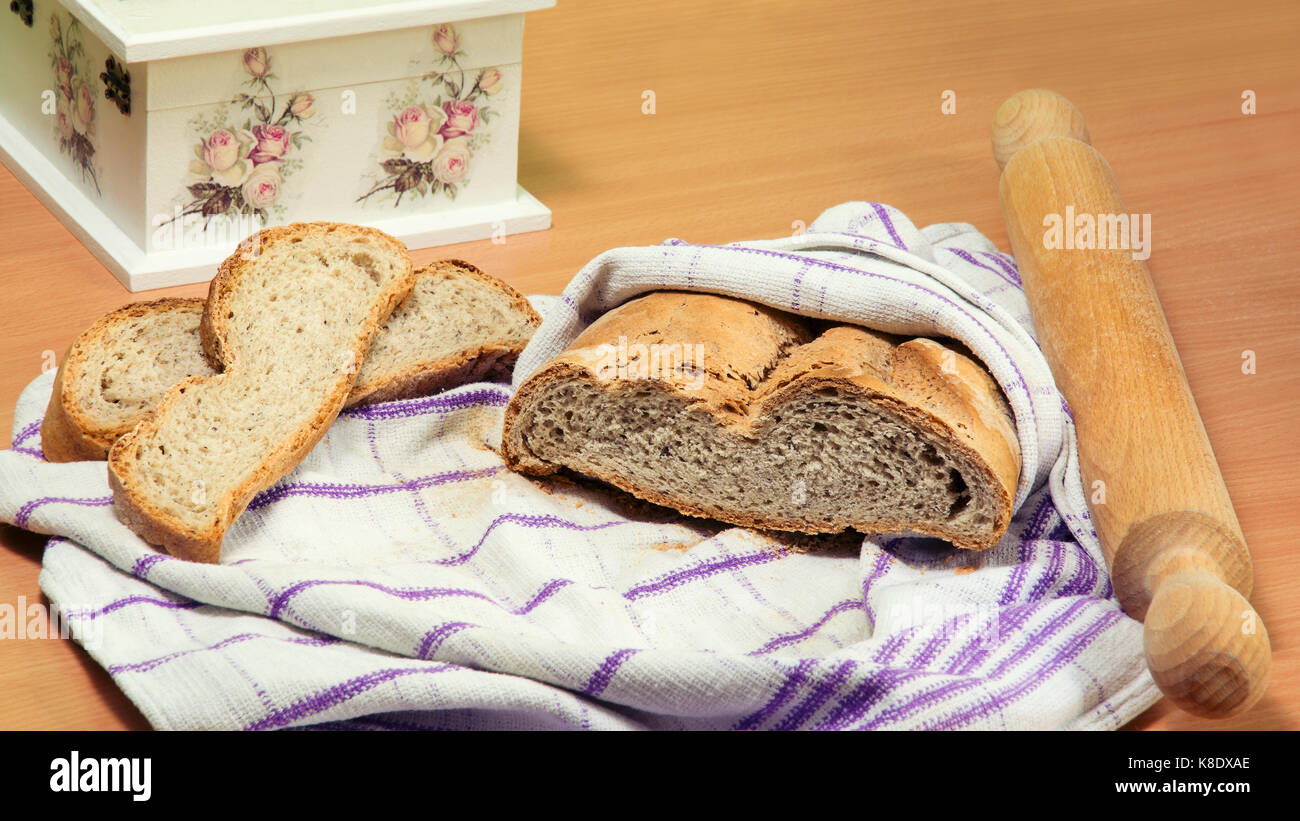 Homemade bread wrapped in kitchen cloth, two bread slices next to it