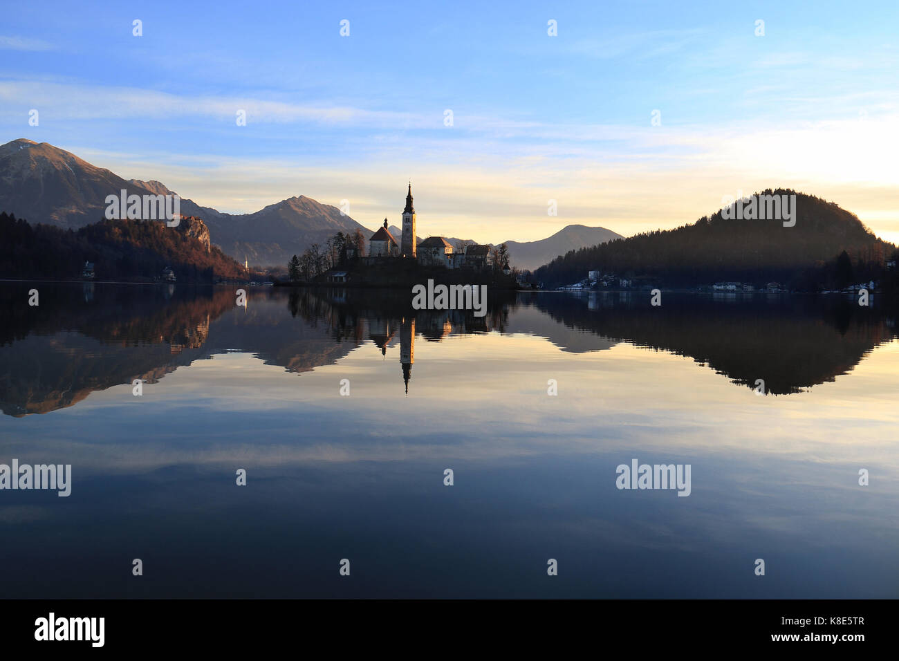 The Assumption Church in the island of Bled with the castle nearby reflecting in the water. Stock Photo