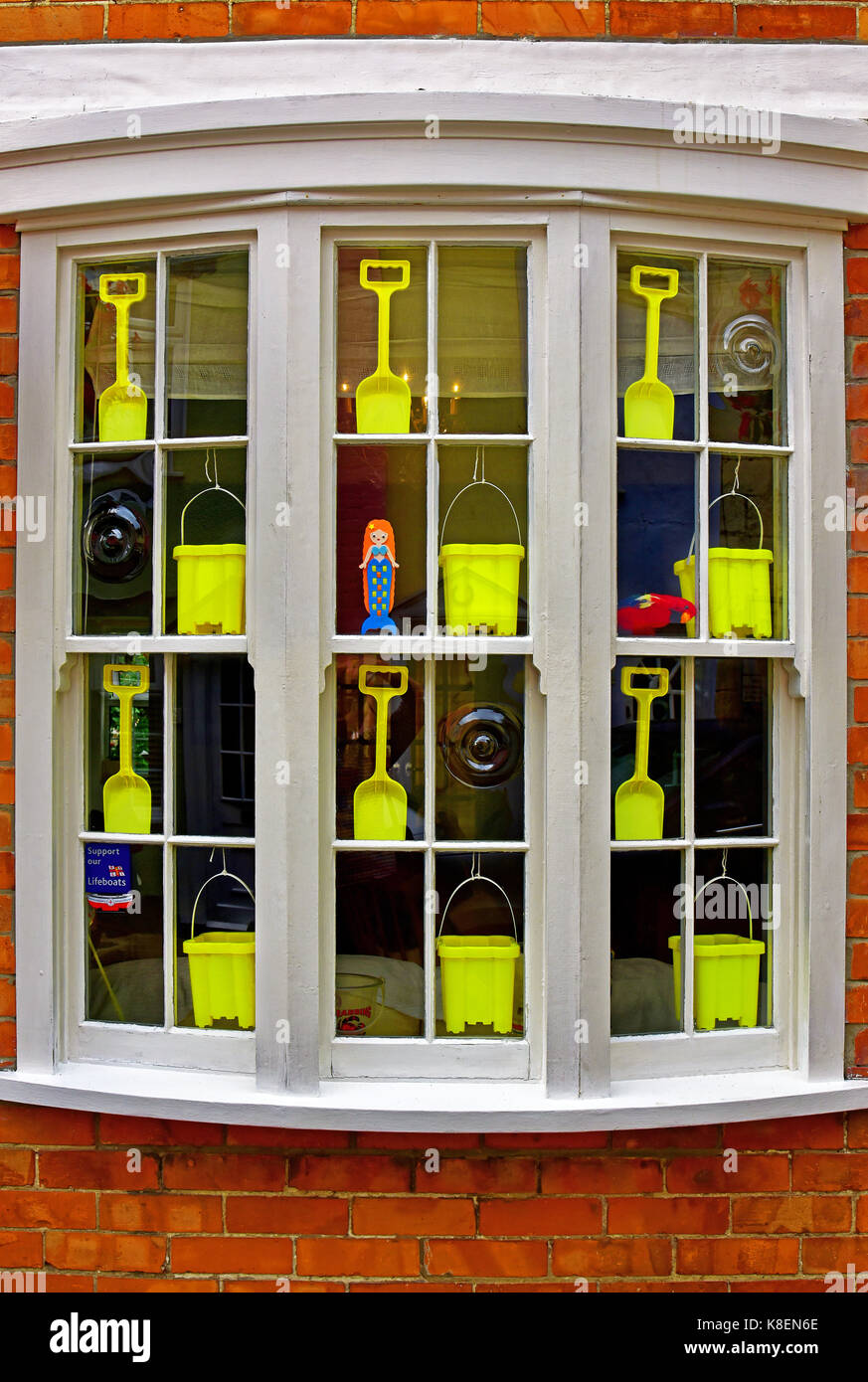 Weymouth Dorset main street window with yellow buckets and spades and RNLI charity box Stock