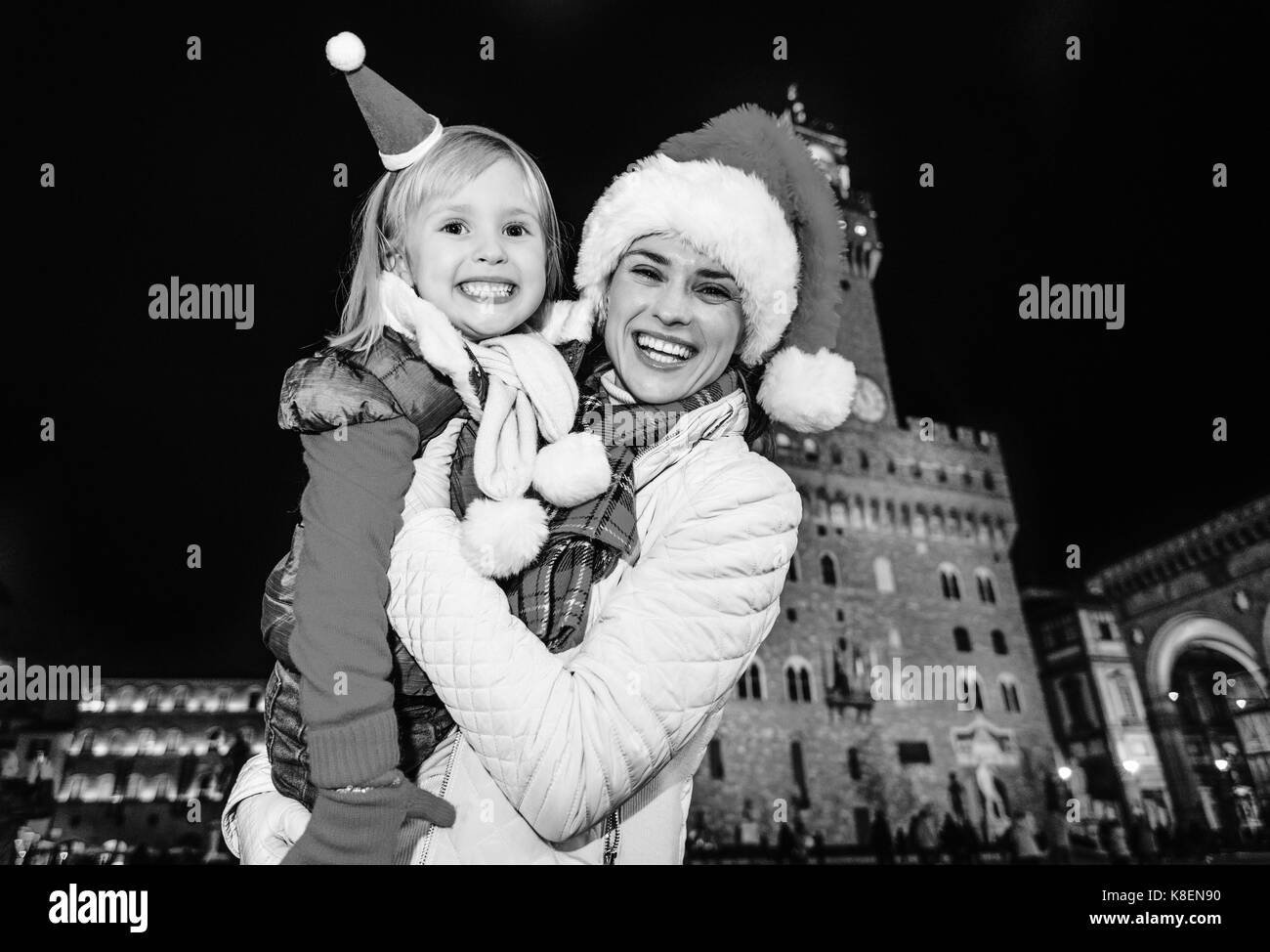 Trip full of inspiration at Christmas time in Florence. Portrait of smiling modern mother and daughter tourists in Christmas hats in the front of Pala Stock Photo