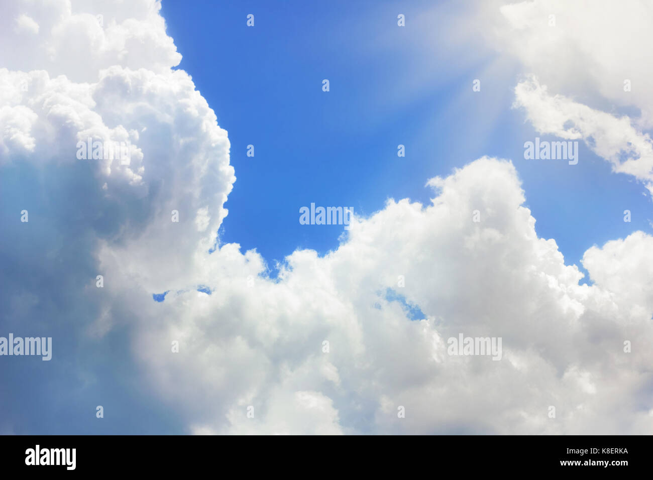 White clouds in blue sky and sun rays Stock Photo