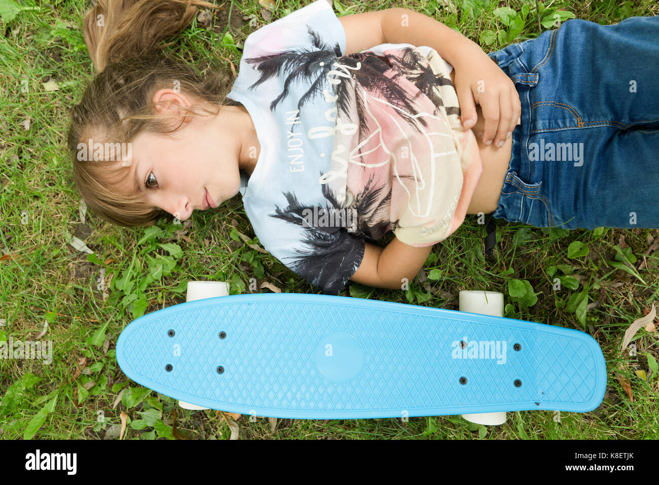 Girl lying on the grass with her skateboard in a park of Pamplona in