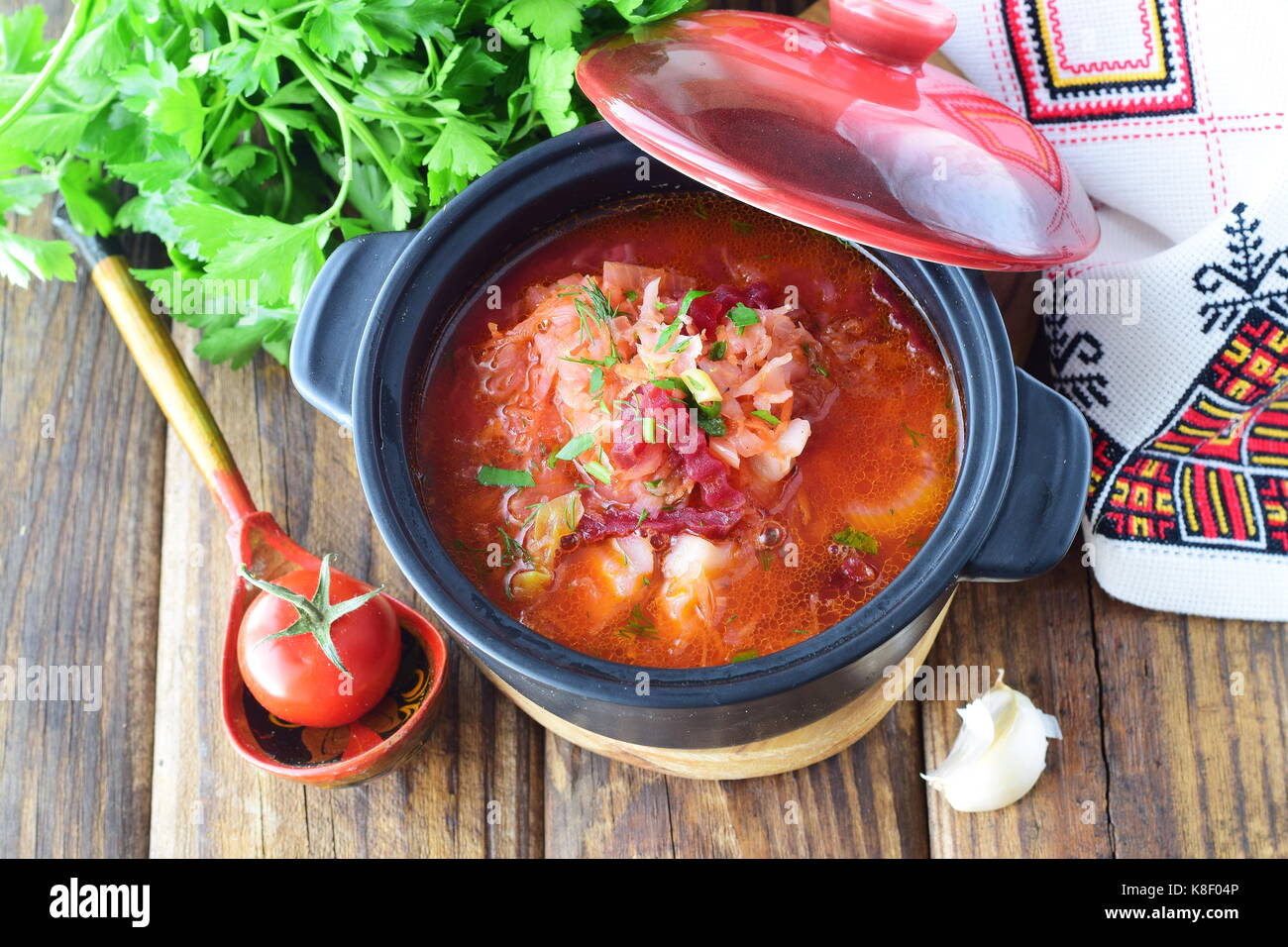 Fasting food. Vegetable soup with sauerkraut, beetroot, carrots, onions, tomato in a black pot on a wooden background. Traditional Eastern European Stock Photo