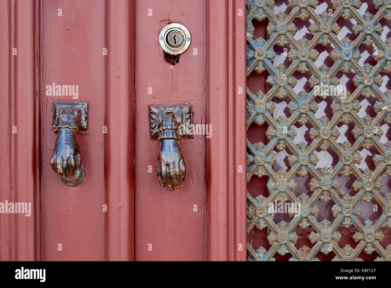 Detail of a red door featuring door knockers in the shape of the Hand of Fatima, in the village of Estoi, Algarve, Portugal. Stock Photo
