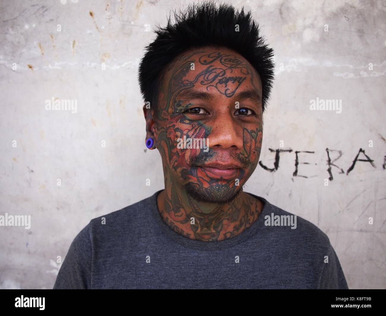 CAINTA, RIZAL, PHILIPPINES - SEPTEMBER 18, 2017: A man with body art shows off his facial tattoo and ear piercing. Stock Photo