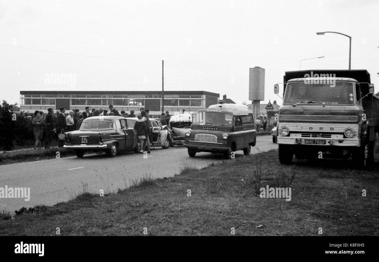 Archive black and white pictures of a car crash between a Cortina and a mini van from the 1960s England with people helping push the cars Stock Photo