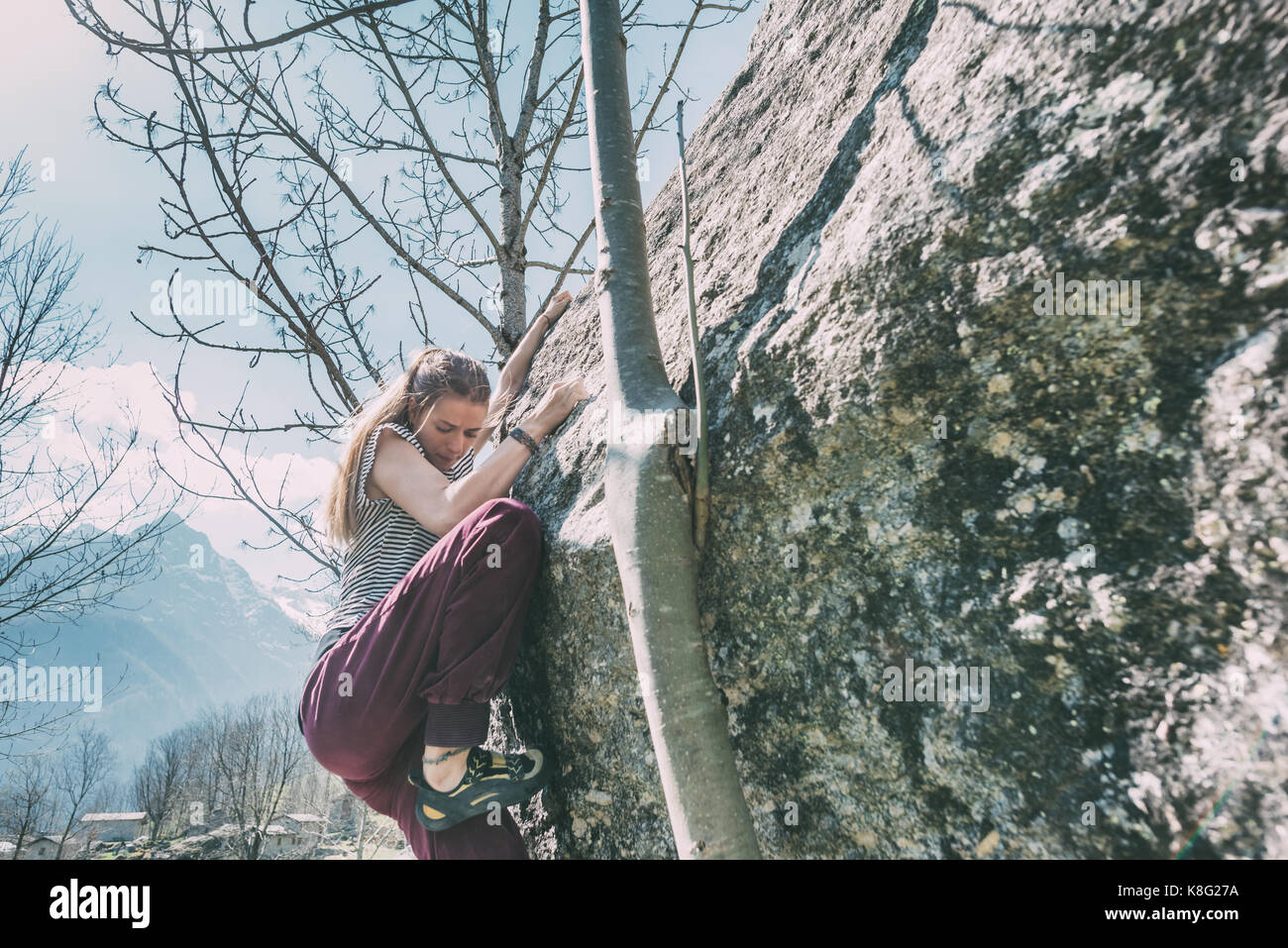 Young female boulderer climbing boulder, Lombardy, Italy Stock Photo