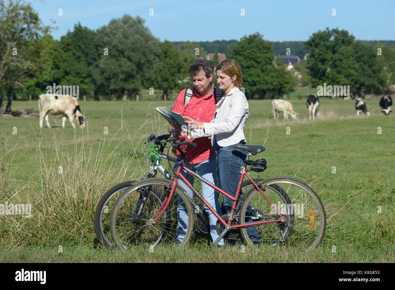 Couple of hikers riding bikes by the River Seine, on the towpath in Sahurs, town belonging to the Regional Natural Park 'Parc Naturel Regional des Bou Stock Photo