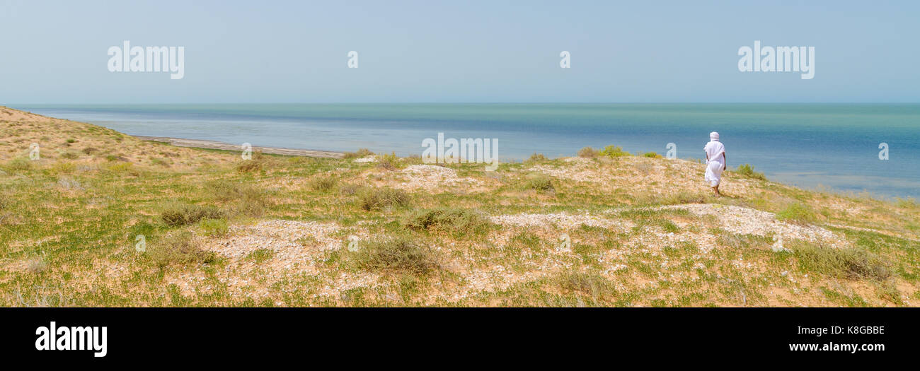 Bedouin in white robe overlooking the Atlantic ocean from dunes in Banc d Arguin National Park, Mauritania, North Africa. Stock Photo