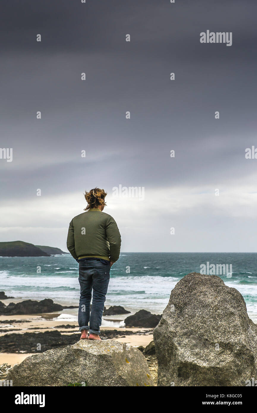 Newquay Cornwall - a barefoot man standing on a rock overlooking Little Fistral in Newquay, Cornwall. Stock Photo