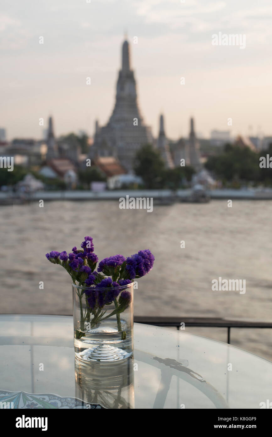Flower vase on a table in a rooftop bar overlooking Wat Arun, Bangkok, Thailand Stock Photo