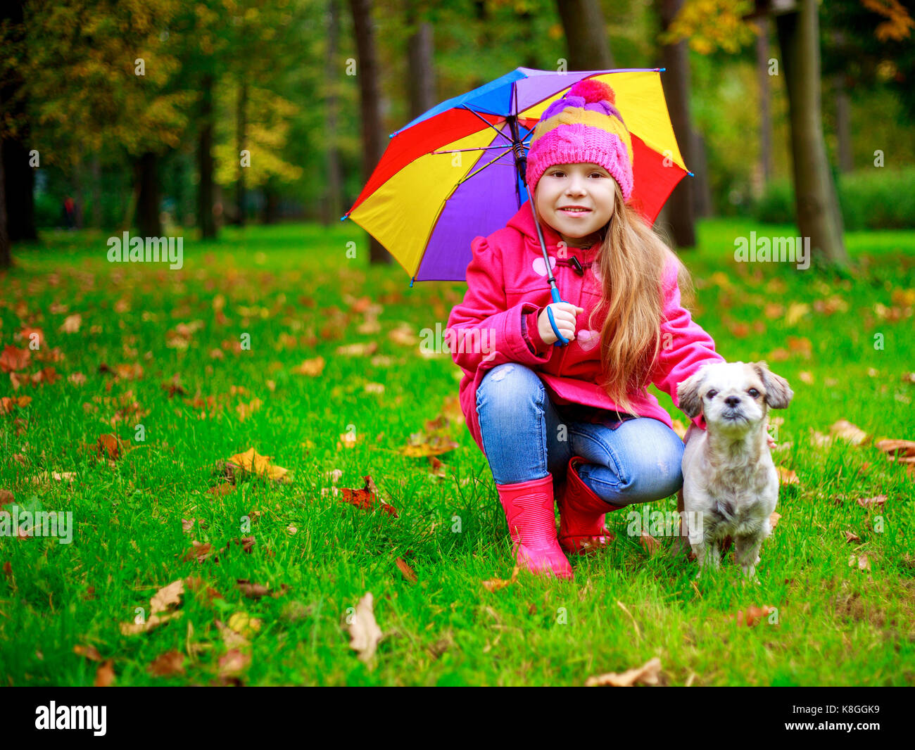 happy girl with her dog and a colorful umbrella in he autumn park Stock ...