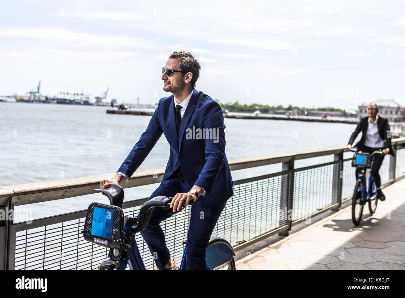 Young businessman cycling on waterfront, New York, USA Stock Photo