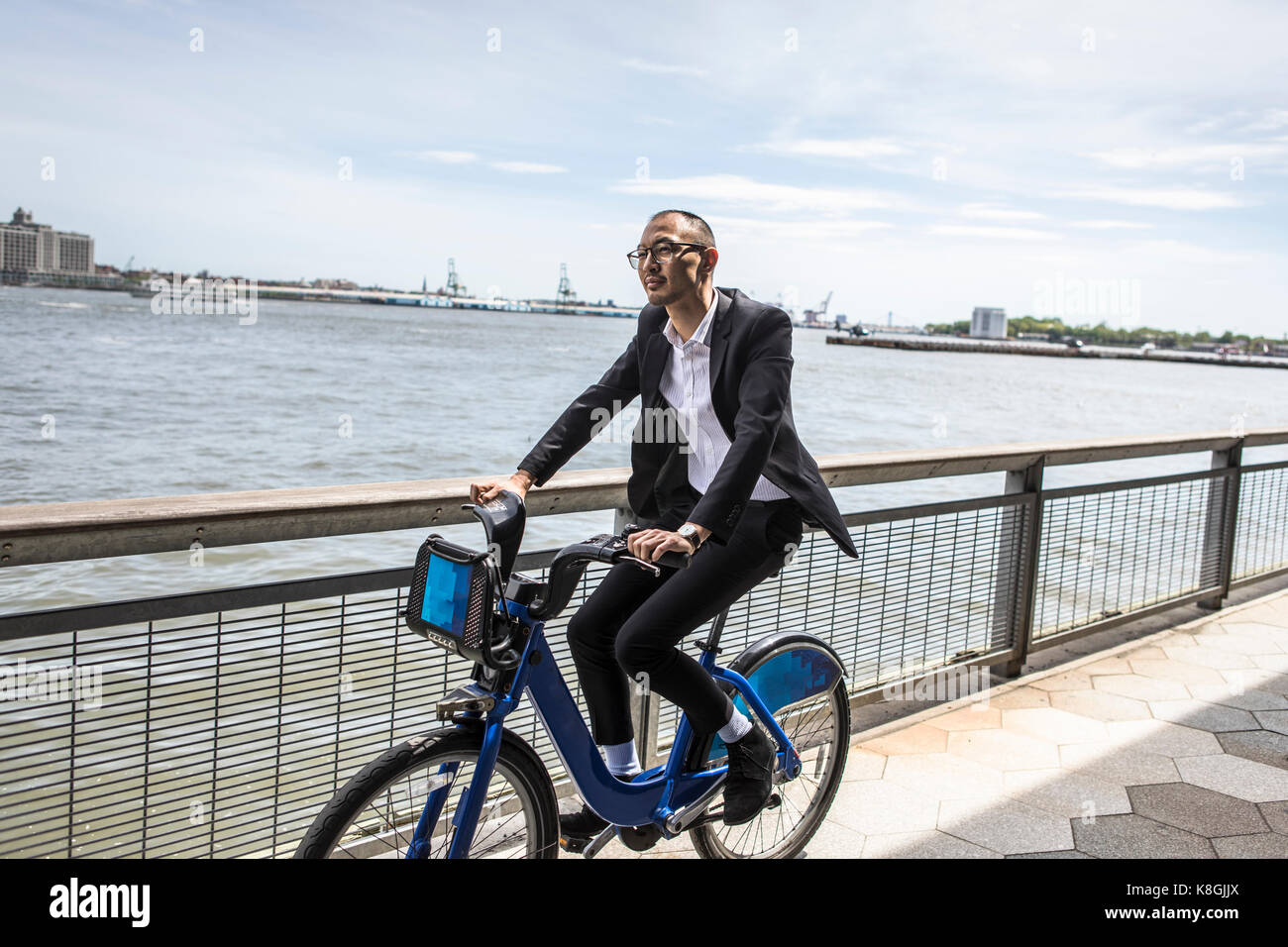 Businessman cycling on waterfront, New York, USA Stock Photo