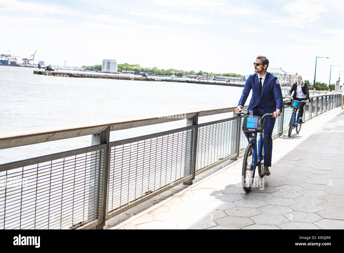 Young businessman cycling on waterfront, New York, USA Stock Photo