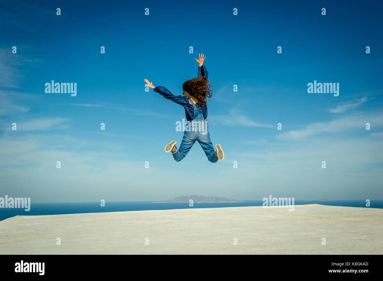 Girl in midair, sea and sky in background, Oía, Santorini, Kikladhes, Greece Stock Photo