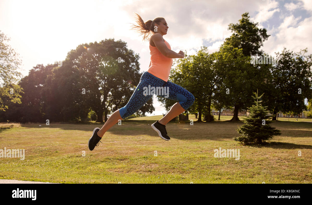 Young woman training in park, leaping mid air Stock Photo