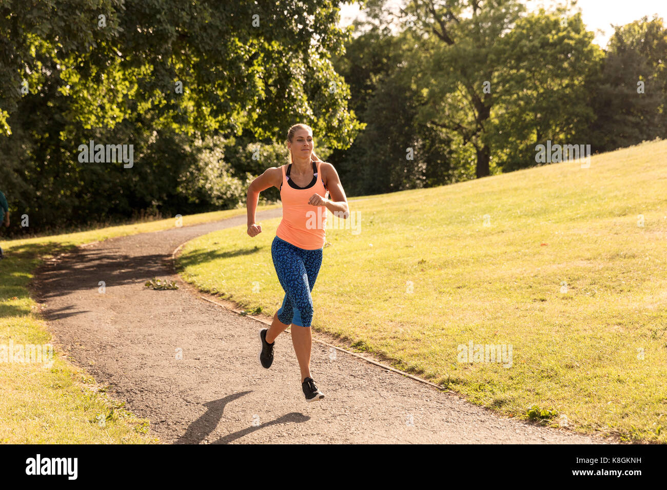 Young female runner running along park path Stock Photo